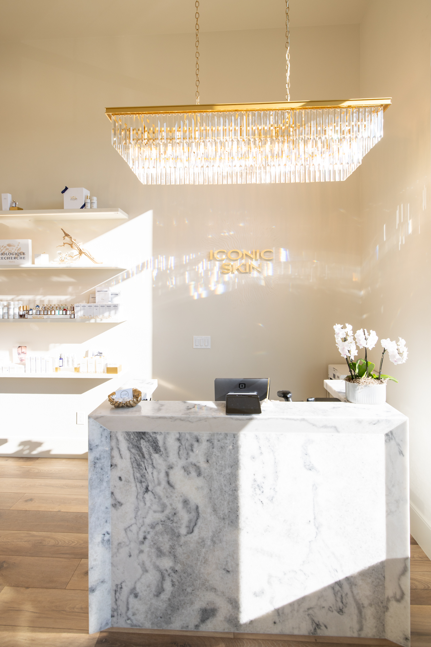 Iconic Skin Boutique front desk in Sugar House, Salt Lake City, with marble reception counter, crystal chandelier, and Biologique Recherche product shelves